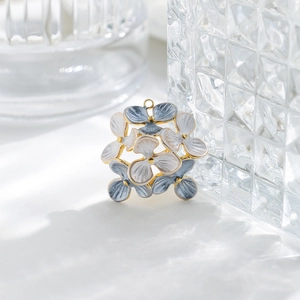 Close-up of gold-plated enamel flower pendant with white and blue petals and hanging loop