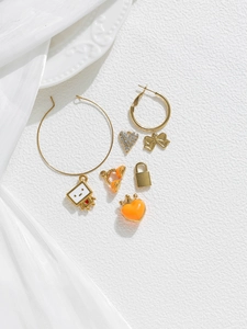Flat lay of gold pendants including enamel robot, bow, heart charms and cubic zirconia pieces