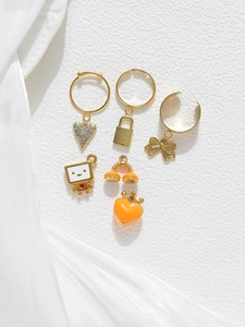 Detailed gold jewelry charm set with heart, lock, and bow pendants on white stone
