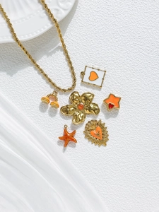 Dettaglio collana a catena dorata a spirale con ciondoli smaltati arancioni a forma di stella