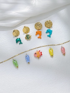 Macro shot of colorful enamel sea creature pendants and gold fish charms on white fabric