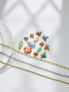 Detail bunter Emaille-Fisch-Anhänger mit goldenen und silbernen Büroklammerketten auf Weiß