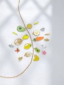 Detailed flat lay of colorful enamel food charms including avocado and fruit on gold chain