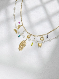 Detail of layered gold feather and butterfly charms with heart pearls on chains