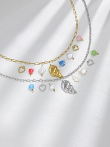 Detailed flat lay of 18K gold plated charms and necklaces with heart and shell pendants