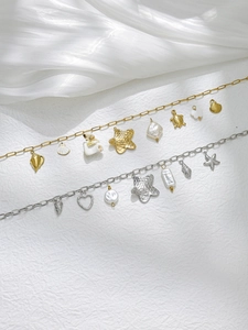 Macro di bracciali marini in oro 18K e argento con ciondoli a forma di conchiglia e perla