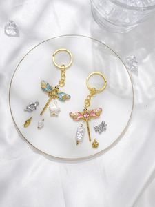 Detailed view of colorful enamel dragonfly charms with gold plating on a white satin cloth