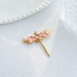 Detail of dragonfly pendant in 18K gold finish with pink enamel wings and drop gem