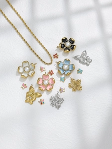 Detailed view of DIY floral and butterfly enamel pendants with golden twist chain links