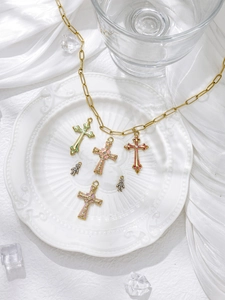 Detailed shot of retro gold cross pendants and paperclip chain on white silk