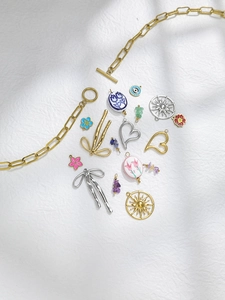 Macro shot of assorted DIY jewelry charms including enamel flowers and gold OT clasps