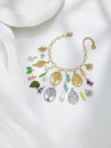 Detailed flat lay of 18K gold tree of life pendants and natural stone bead charms