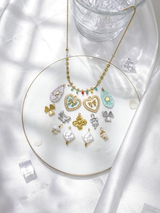 Detail of bohemian 18K gold stainless steel pendants with butterfly and clover charms