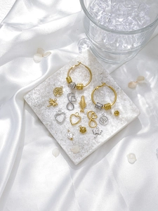 Detailed collection of gold and silver heart and tree pendants on white stone surface
