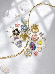 Artistic detail of French vintage style enamel flower, snake and star charms on rock