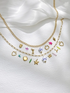 Detailed shot of layered gold charms including heart, starfish, and colorful pendants