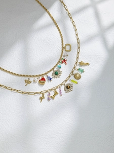 Detail of 18K gold-plated charms including evil eye, heart, and sunflower on mixed chains