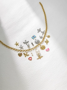 Détail du collier à chaîne dorée avec pendentifs émaillés abeille, soleil et cœur