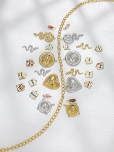 Detalle de dijes en oro de 18 quilates y plata con serpiente, corazón y placas de esmalte
