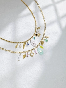Detail of layered gold rope and paperclip chains with mixed owl and leaf pendants