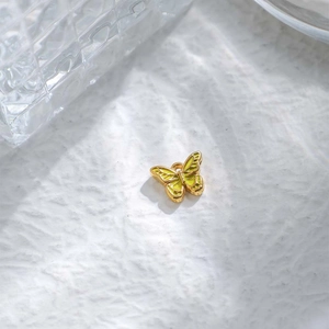 Detalle de un colgante de mariposa de acero 304 con esmalte amarillo y anillo para joyas DIY