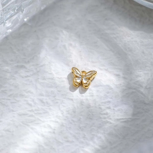 Vista detallada de un colgante de mariposa en acero inoxidable dorado con esmalte blanco