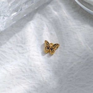 Detalle macro de un colgante de mariposa bañado en oro de 18K con esmalte negro