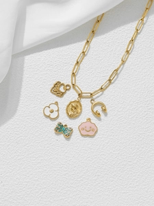 Détail d'une chaîne dorée avec charms fleur, casque et émail coloré sur de la soie
