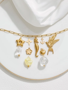 Detailed view of 18K gold plated charms featuring sea horse and star shapes on a tray