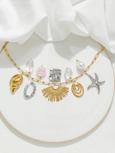 Detailed view of a gold paperclip chain necklace with 10 mixed charms on a white tray