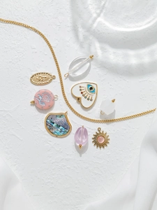 Detalle de dijes de acero dorado con motivos de ojo de la suerte y serpiente