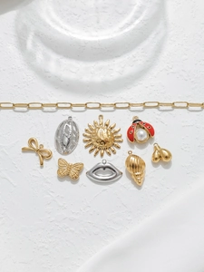 Artistic layout of assorted gold and silver jewelry charms on a white textured background