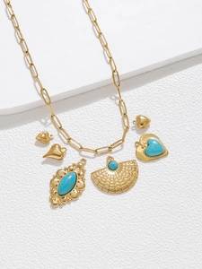 Bohemian gold necklace with turquoise heart and fan pendants on a white stone background
