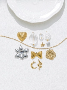 Flat lay of gold snake, heart, and flower charms for DIY jewelry making with thin gold chain