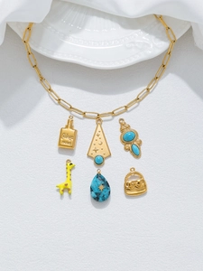 Dettaglio della collana a catena d'oro con ciondoli a profumo e giraffa su fondo bianco