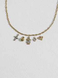 Detail of gold chain necklace featuring cross, bell, girl, and heart shaped pendants