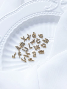 Nahaufnahme goldener Buchstabenanhänger mit Zirkonia für DIY Schmuckherstellung