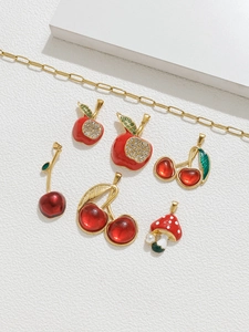 Detalle de colgantes de frutas y setas esmaltados en rojo con cadenas doradas