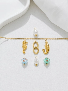 Macro detail of DIY jewelry kit with golden seahorse, pearl charms and cat paw beads