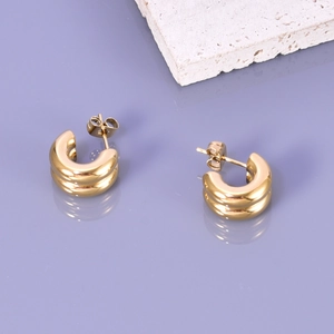 Macro shot of gold double-layered C-shaped chunky hoop earrings on a stone base