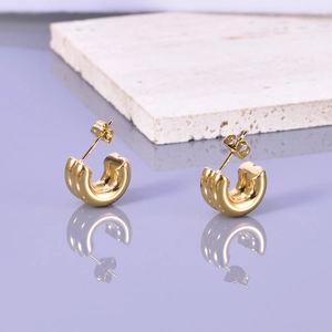 Macro shot of 18K gold-plated C-shaped heart earrings on a purple reflective mirror