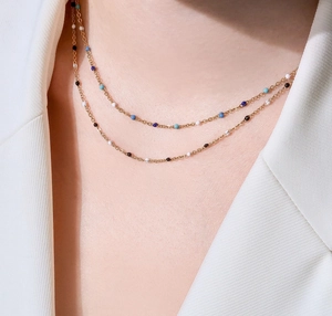 Primer plano de un collar de doble capa de oro con cuentas de esmalte de colores en modelo
