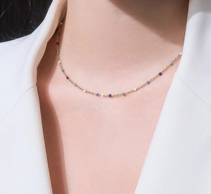 Primer plano de collar dorado con cuentas de esmalte azul degradado lucido por la modelo