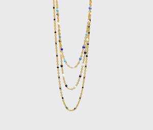 Detalle de un collar dorado de varias capas con cuentas esmaltadas azules y blancas