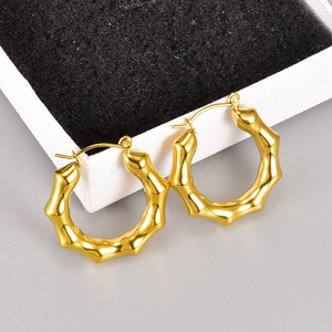 Polierte 18K Gold-Ohrringe im Bambus-Design mit weißer Schmuckschachtel auf grauem Grund