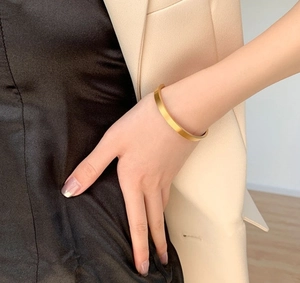 Minimalist 18K gold plated C-shaped matte cuff bracelet shown on elegant female model
