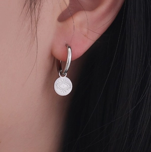 Minimalist evil eye hoop earrings in silver stainless steel, worn by a female model