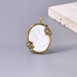 Detailed view of oval shell pendant with 18k gold plating and zircon leaf accents