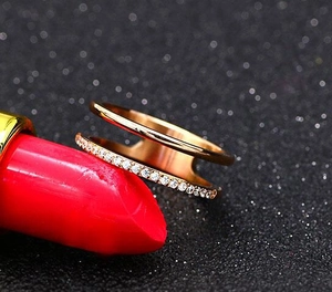 Nahaufnahme von roségoldenem Doppelring mit Mikropavé-Kristallen auf rotem Lippenstift