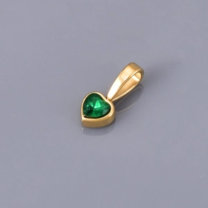 Macro shot of a heart-shaped green gemstone pendant with polished gold plating